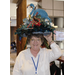 A woman wearing a large hat with a blue flamingo and other decorations 