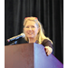 A woman standing at a podium smiling while speaking to the crowd