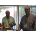 Two gentlemen standing at a table smiling at the camera