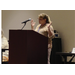 A woman speaking at a podium gesturing with both hands