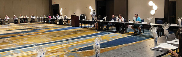 A group of people seated at long tables arranged in a square