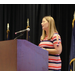 A woman singing into a microphone at a podium