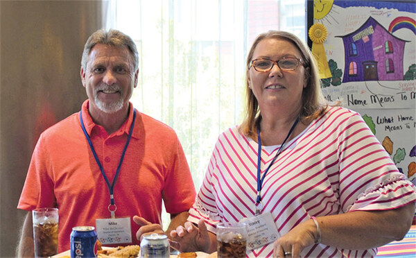 a man and a woman standing smiling at the camera