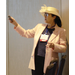 A woman in a large pink hat pointing towards a screen
