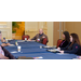 Men and women sit around a table smiling and listening.