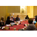 Women are seated around a table taking notes and listening.