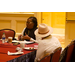 Patricia Allen sits at a table and speaks as another woman looks on. 