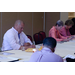 Men and women sitting at a table, taking notes and listening.