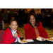 Two women sit together smiling as they share a meal.