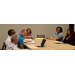 6 members sit around a table laughing and talking together. 