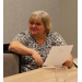 Connie Howard, ED (Fort Mill, SC) sits at a table, holding a sheet of paper and smiling. 