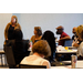 A woman stands to her left and speaks to a room of people.