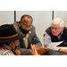 Two men and a woman sit at a table and talk with one another.