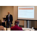 A man stands to the left of a presentation he is giving. 