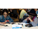 Two women sit at a table together while one takes notes.