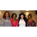 Four women stand together, smiling.