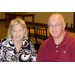 A man and a woman sit together and smile at the camera.