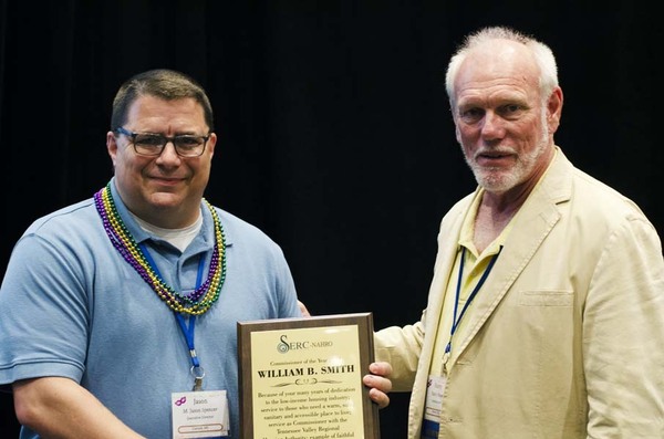 Two men holding an award and smiling