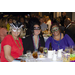 Three women sitting at a table and wearing masks