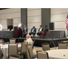  A panel of four speakers are sitting on a stage in a large conference room. 