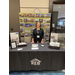 A woman standing behind the booth table for REB Architects.