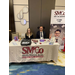 A man and a women sitting behind a booth table for the accounting company, Smith Marion and Co. 