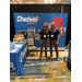 Two men standing side by side in front of a booth for Chadwell Supply.
