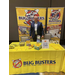 A man standing proudly behind a large booth for Bug Busters. 