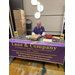 An older man sitting behind a booth table for Lane and Company.