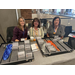 Three ladies sitting behind a table to pass out name tags.