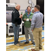 Three man stand in a group talking to one another.