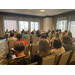 A large group gathers in a room for a business meeting. 