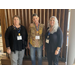 Three women standing next to each other with name badges on.