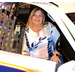 A women sitting in a race car while smiling.