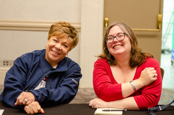 Two ladies sitting together and smiling.