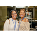 Two women standing along side of eachother smiling.