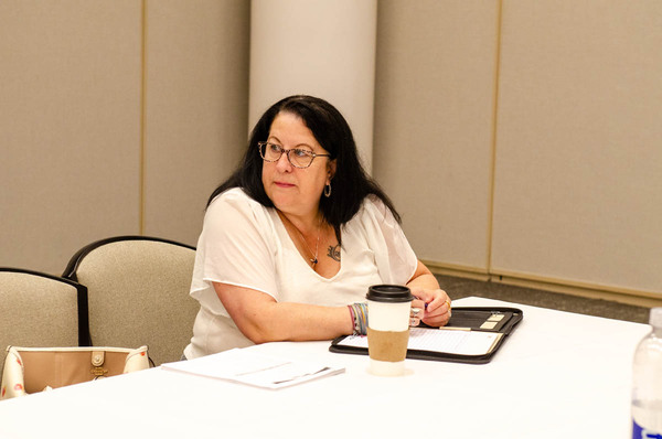 Dark haired lady seated at the Admin Practices Committee meeting.