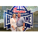  A man in a blue check shirt and a woman in a white top at the Executive Committee dinner in front of a Chick-fil-a sponsored College Football Hall of Fame sign. 