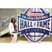  Woman in a white and black outfit at the Executive Committee dinner in front of a Chick-fil-a sponsored College Football Hall of Fame sign. 