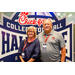  A man and woman standing in front of a Chick-fil-a sponsored College Football Hall of Fame sign. 