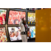  A woman standing with her fist up in front of a wall filled with various photos of sporting events. 