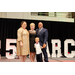  Two women, a man, and a small boy smile for a photo on the stage. 