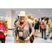  A man wearing a hat and lei walking through a crowded room. 
