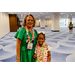  A woman with a rainbow lei standing with a little girl that is wearing two leis: one pink and one green. 