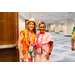  Two women in bright colorful clothing wearing leis and event badges. 