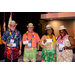  Four individuals in Hawaiian themed outfits smiling as they each hold up white cards. 