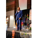 A man wearing a blue suit speaking into a microphone on stage. 