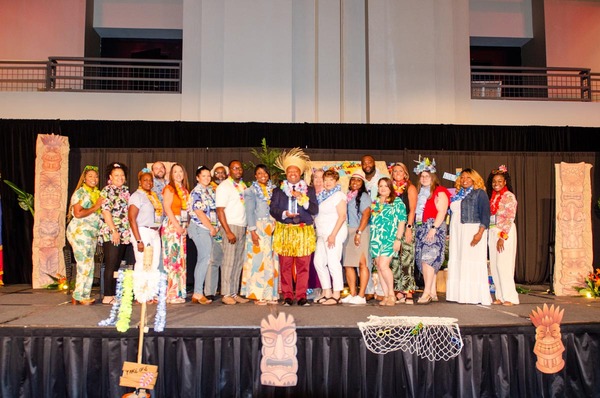 A group of people standing on stage for a huge group photo. Anthony Goodson, Jr. is standing in the middle holding a glass award.