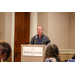  A gentleman standing behind a podium that says Sheraton Greensboro. 