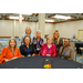  Seven women sitting and standing around a table with a black table cloth. 
